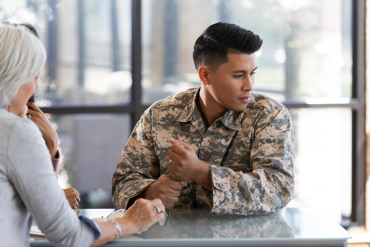 Soldier in camouflage uniform discusses important matters with civilian woman in meeting